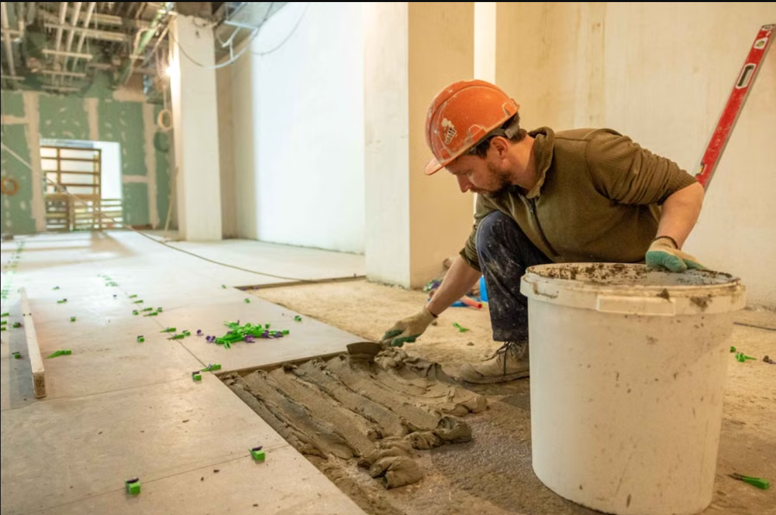 Tile mason laying floor tiles during a renovation